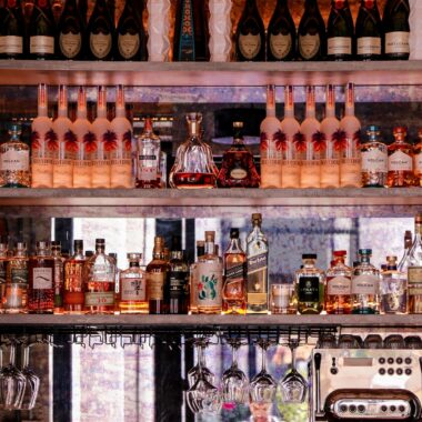 A well-stocked bar display featuring various bottles of liquor and glassware, perfect for nightlife scenes.