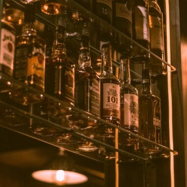 Captivating display of whiskey bottles on shelves with warm, atmospheric lighting in a bar setting.
