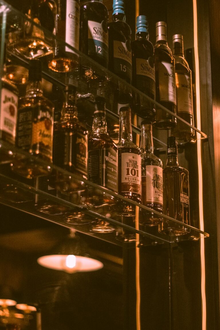 Captivating display of whiskey bottles on shelves with warm, atmospheric lighting in a bar setting.