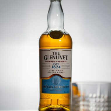 Elegant single malt Scotch whisky bottle with glass against studio background.