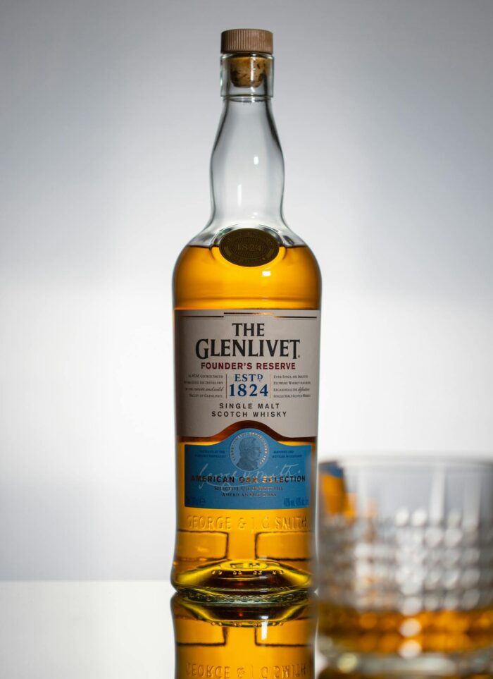 Elegant single malt Scotch whisky bottle with glass against studio background.