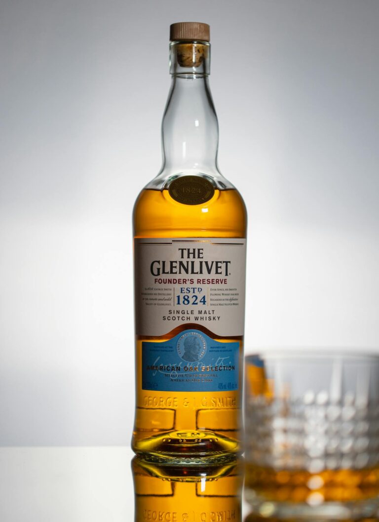 Elegant single malt Scotch whisky bottle with glass against studio background.