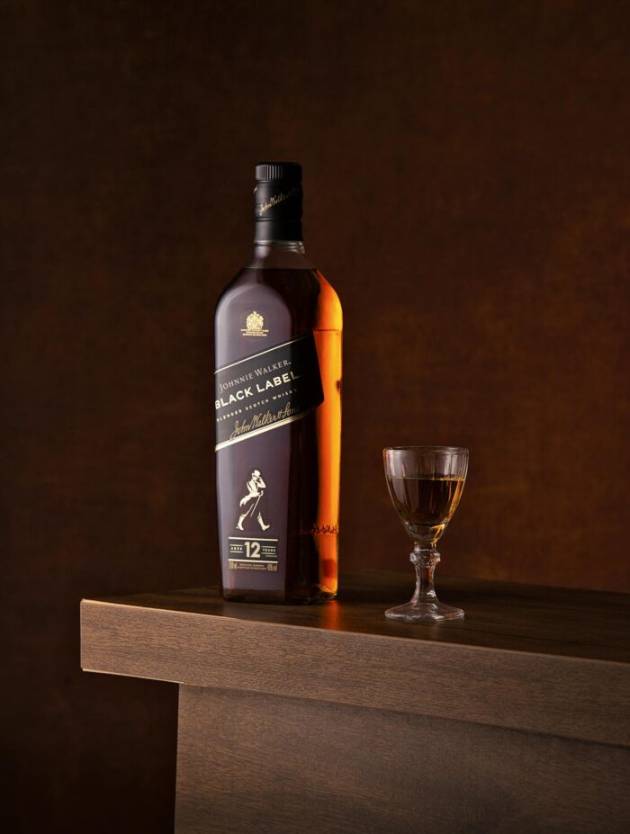 Luxurious bottle of whiskey with a glass on a wooden surface, perfect for premium beverage advertising.