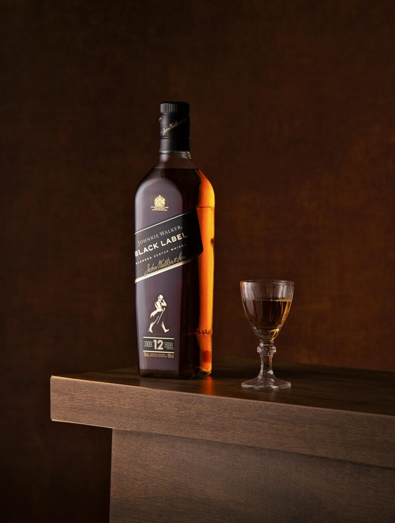 Luxurious bottle of whiskey with a glass on a wooden surface, perfect for premium beverage advertising.